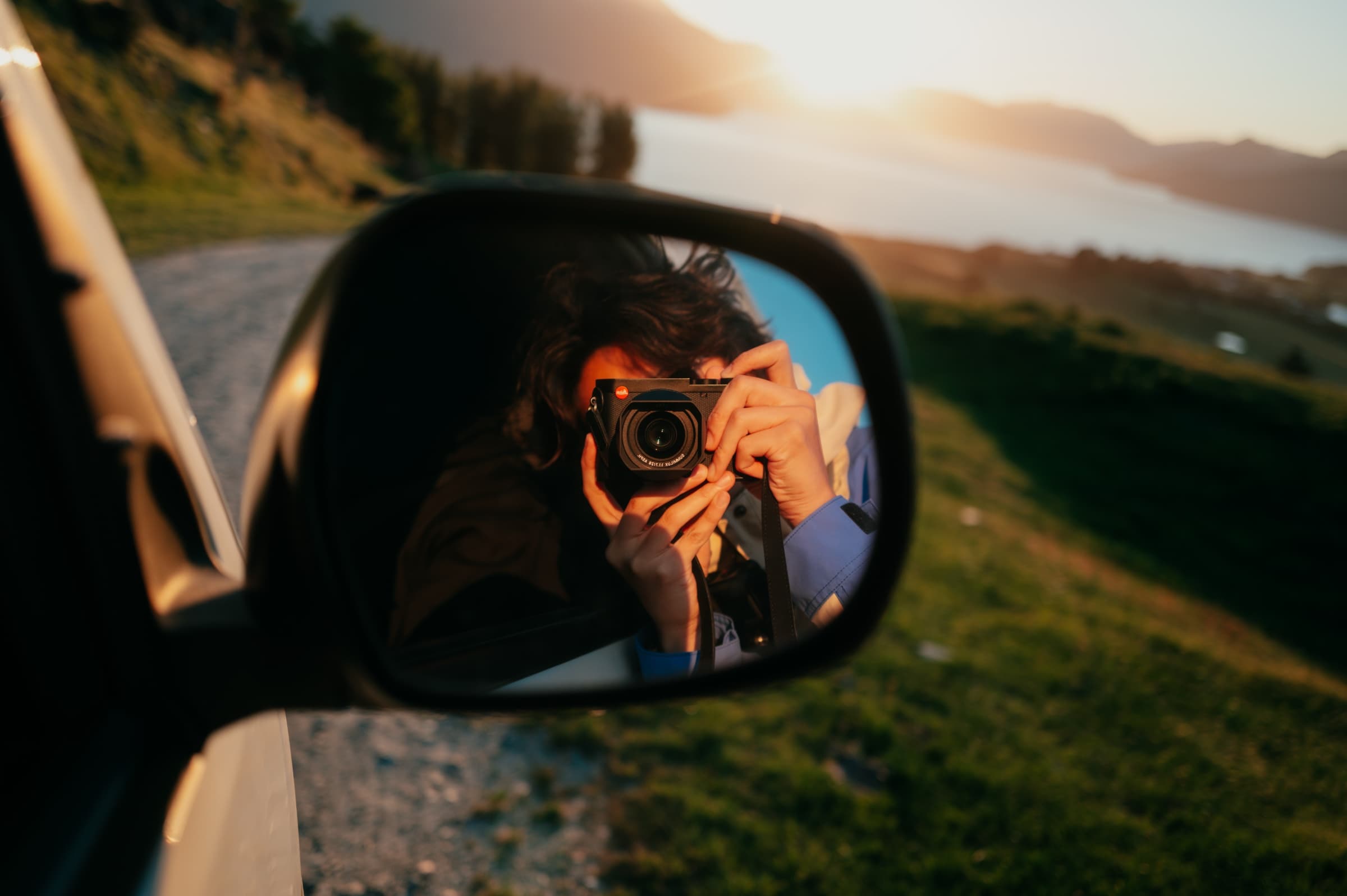 Hojae holding a Leica Q3, reflected in a car mirror